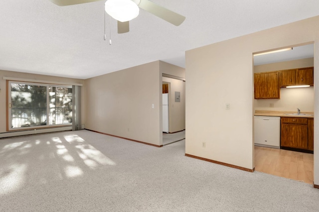 unfurnished living room with baseboard heating, ceiling fan, light carpet, and sink