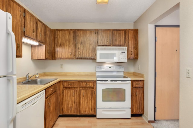 kitchen with white appliances, light hardwood / wood-style floors, a textured ceiling, and sink