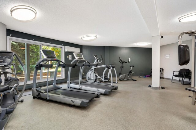 gym with an AC wall unit and a textured ceiling