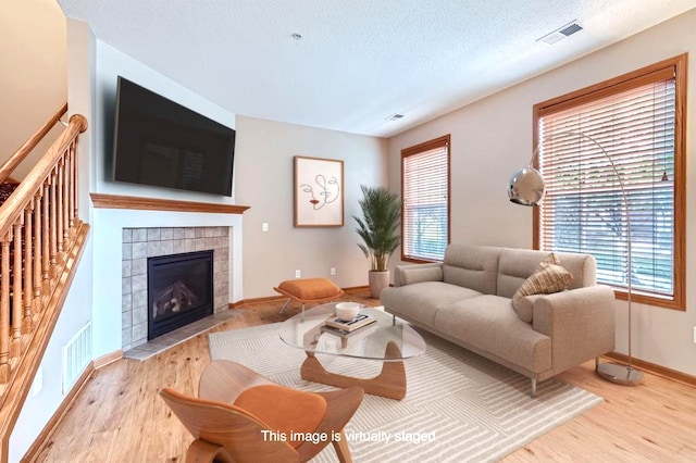 living room with a fireplace, a textured ceiling, and light hardwood / wood-style floors