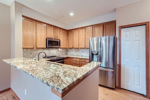 kitchen featuring kitchen peninsula, decorative backsplash, stainless steel appliances, and light stone countertops