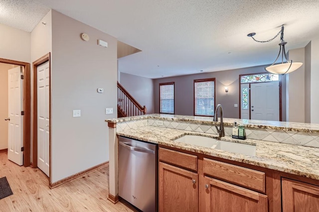 kitchen featuring light stone countertops, sink, pendant lighting, light hardwood / wood-style flooring, and dishwasher