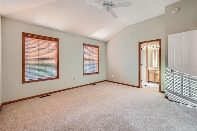 unfurnished bedroom with connected bathroom, light colored carpet, ceiling fan, and lofted ceiling