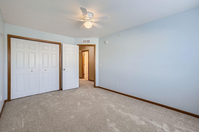 unfurnished bedroom with ceiling fan, light carpet, and a closet