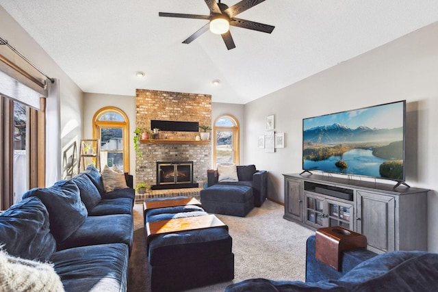 carpeted living room with ceiling fan, vaulted ceiling, and a brick fireplace