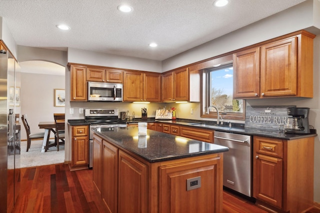 kitchen with stainless steel appliances, a kitchen island, sink, and dark hardwood / wood-style flooring