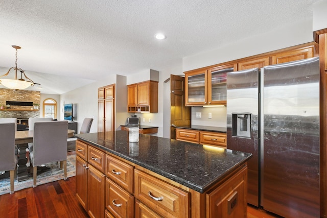 kitchen featuring pendant lighting, dark wood-type flooring, stainless steel refrigerator with ice dispenser, a textured ceiling, and a kitchen island