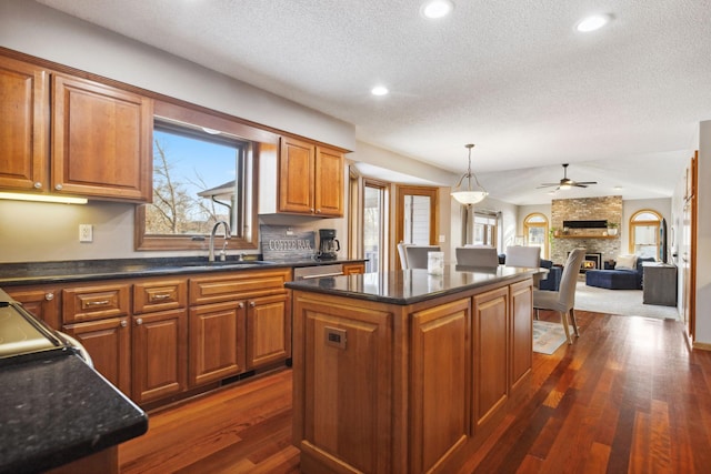 kitchen featuring dark hardwood / wood-style floors, pendant lighting, a fireplace, sink, and a center island