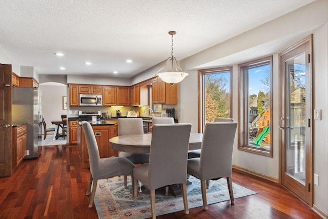 dining area featuring sink, a textured ceiling, and dark hardwood / wood-style flooring