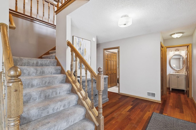 stairs featuring wood-type flooring and a textured ceiling