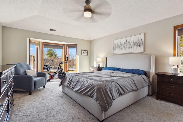 bedroom featuring ceiling fan, light carpet, and a textured ceiling