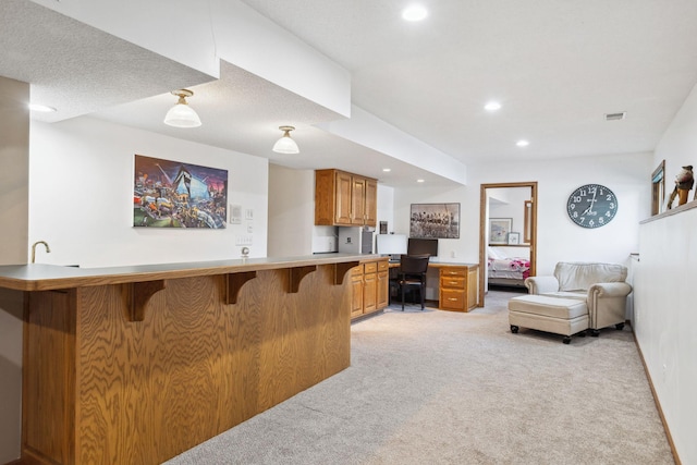 kitchen with built in desk, light colored carpet, a kitchen bar, and kitchen peninsula