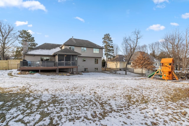 snow covered property featuring a playground, a deck, and a sunroom