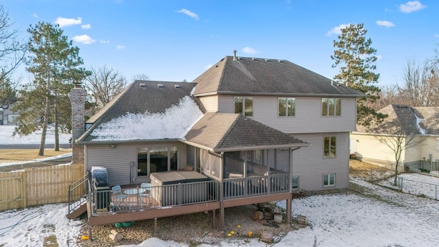 snow covered property with a deck and a sunroom