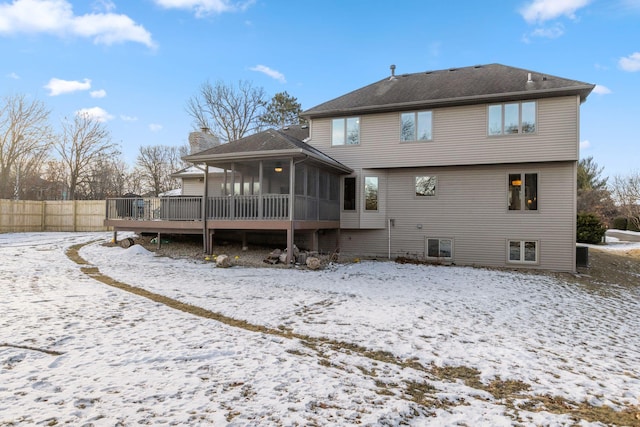 snow covered property featuring a wooden deck and a sunroom