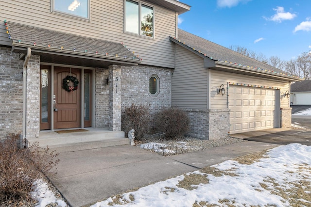 snow covered property entrance with a garage