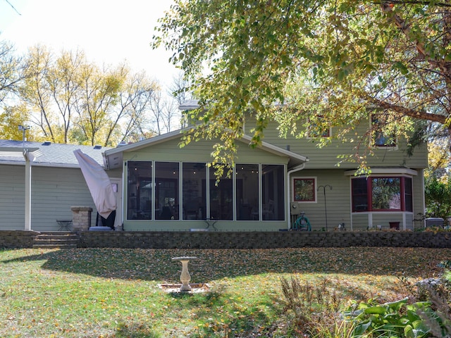 rear view of house featuring a yard and a sunroom