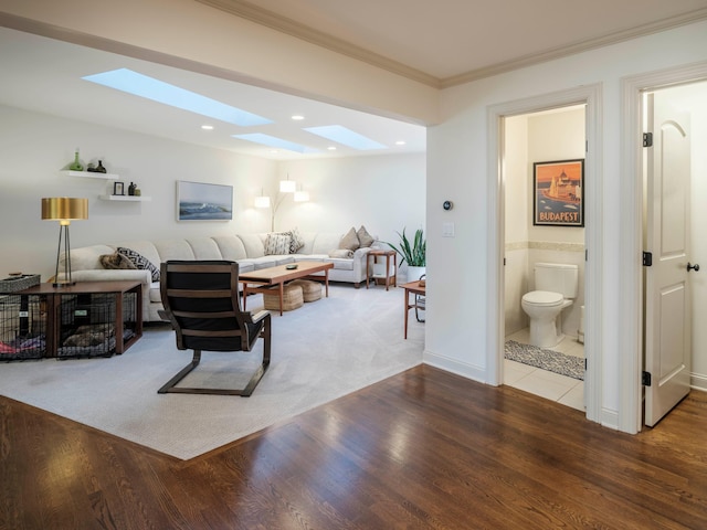 living room with wood-type flooring, a skylight, and crown molding