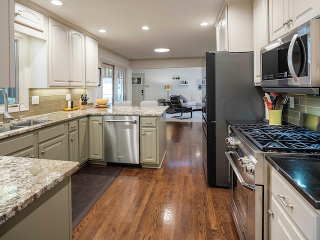 kitchen featuring stainless steel appliances, dark wood-type flooring, light stone counters, and kitchen peninsula