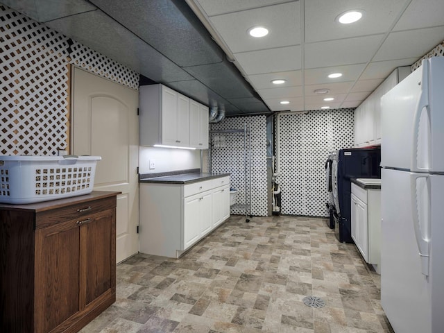 kitchen featuring white fridge, white cabinets, and a paneled ceiling