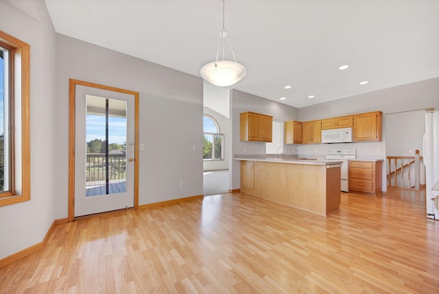 kitchen with kitchen peninsula, white appliances, sink, decorative light fixtures, and light hardwood / wood-style flooring