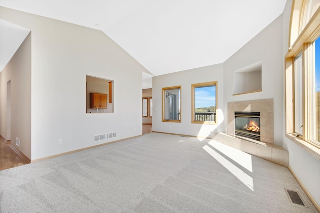 unfurnished living room with a high end fireplace, light colored carpet, and lofted ceiling