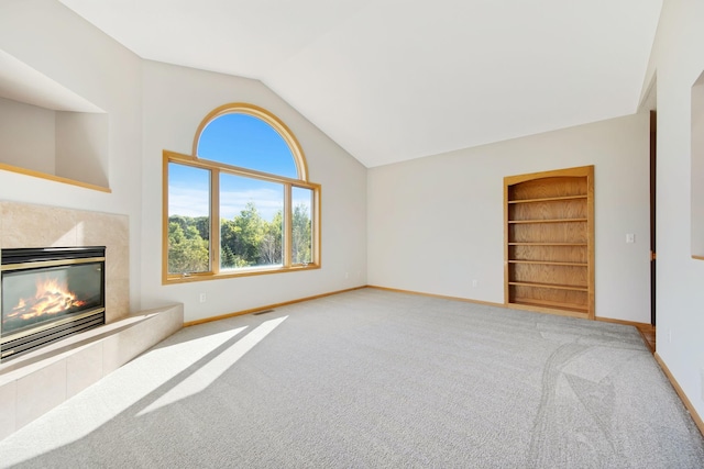 unfurnished living room featuring carpet, built in shelves, a fireplace, and vaulted ceiling