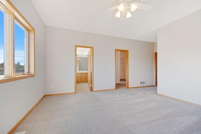 unfurnished bedroom featuring ensuite bath, light colored carpet, ceiling fan, a spacious closet, and a closet