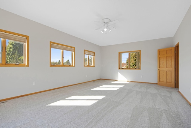 unfurnished room featuring light colored carpet, a wealth of natural light, and ceiling fan