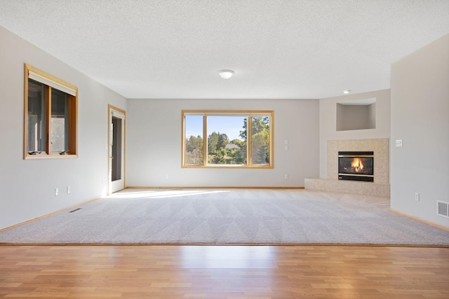 unfurnished living room with a fireplace, a textured ceiling, and light hardwood / wood-style flooring