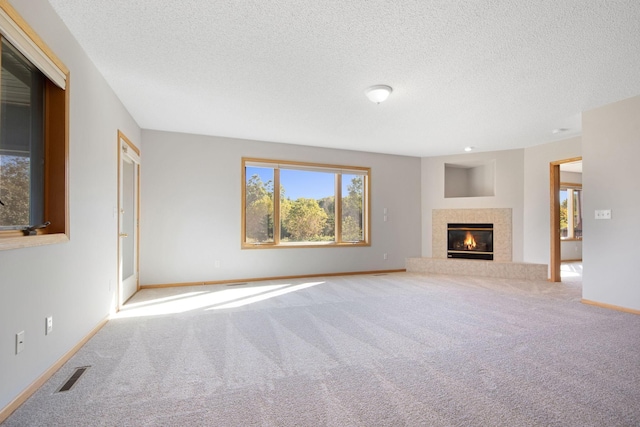 unfurnished living room featuring a tile fireplace, a textured ceiling, and carpet flooring