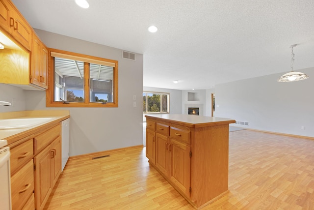 kitchen with pendant lighting, a center island, white dishwasher, sink, and light hardwood / wood-style floors