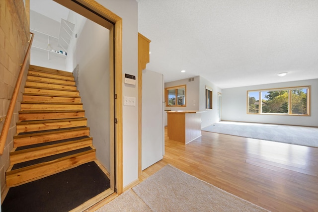 stairs with hardwood / wood-style floors and a textured ceiling