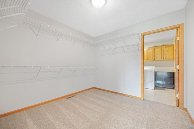 spacious closet featuring light carpet and washer / dryer