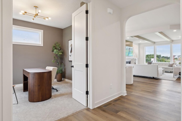 interior space with an inviting chandelier, wood-type flooring, and beamed ceiling