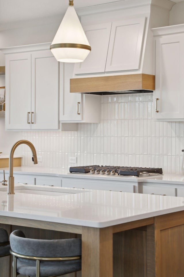 kitchen featuring stainless steel gas stovetop, white cabinetry, and tasteful backsplash