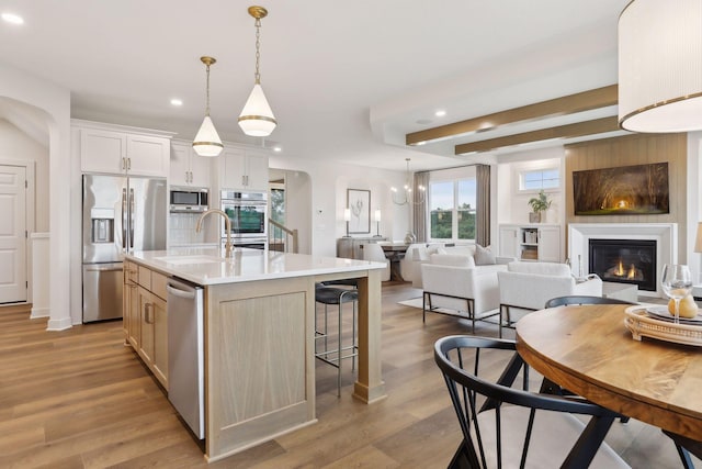 kitchen with sink, white cabinetry, an island with sink, pendant lighting, and appliances with stainless steel finishes