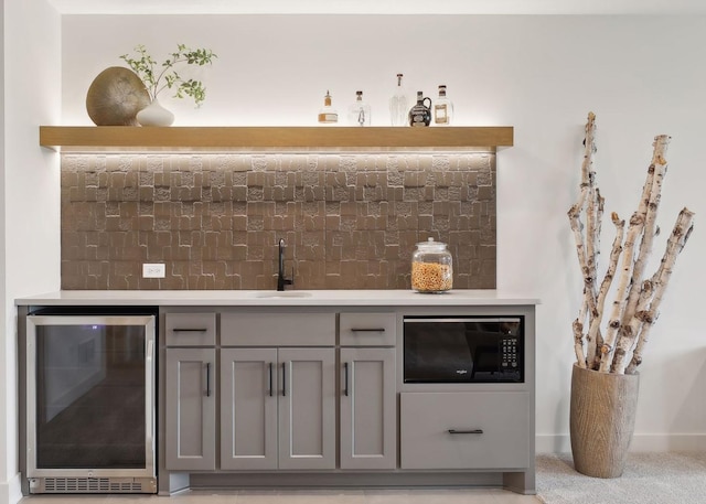 bar with black microwave, sink, gray cabinetry, and wine cooler