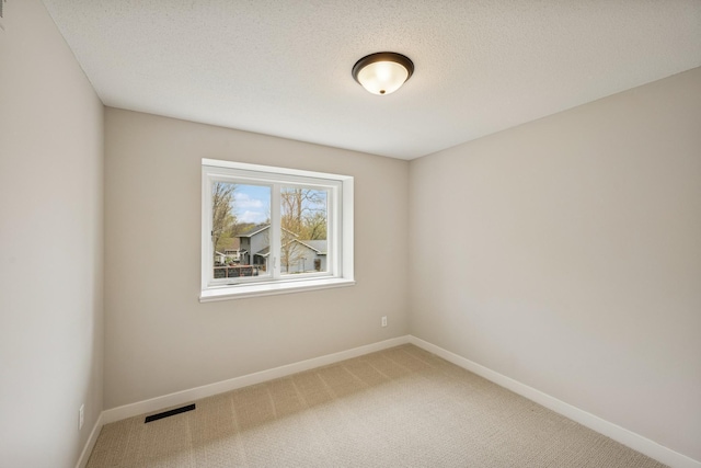carpeted spare room featuring baseboards and visible vents
