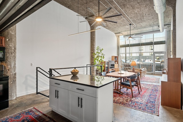 kitchen with concrete flooring, white cabinetry, floor to ceiling windows, and range