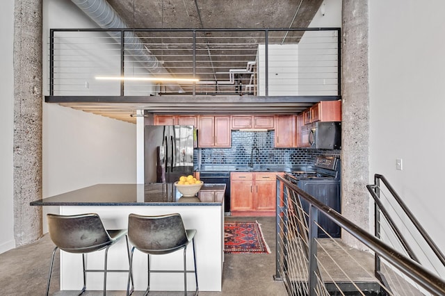 kitchen with a breakfast bar area, sink, decorative backsplash, and black appliances