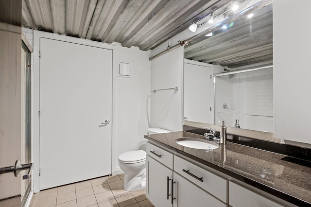 bathroom featuring tile patterned flooring, vanity, a shower with shower door, and toilet