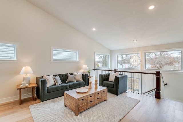 living room featuring light hardwood / wood-style floors, high vaulted ceiling, and a chandelier