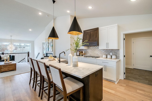 kitchen with light hardwood / wood-style flooring, white cabinets, pendant lighting, and lofted ceiling