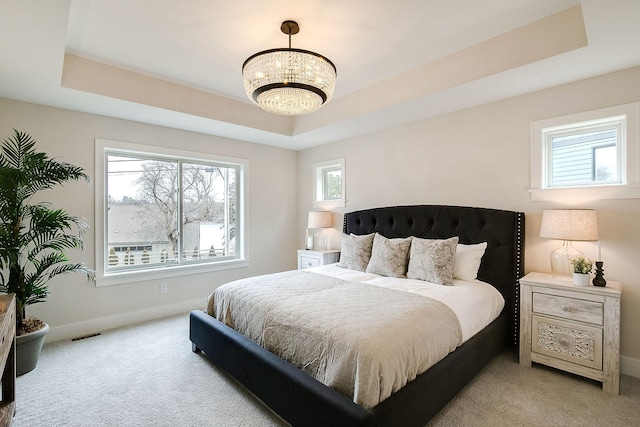 bedroom with light carpet and a tray ceiling