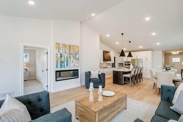 living room featuring light wood-type flooring and high vaulted ceiling