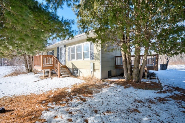 snow covered back of property featuring a wooden deck