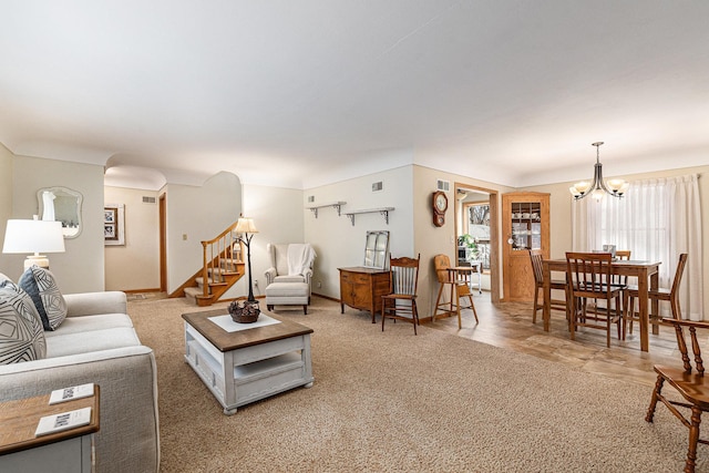 living area featuring light carpet, baseboards, stairs, and a chandelier