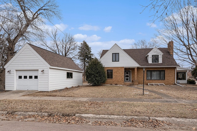 view of front of home with a chimney, a detached garage, roof with shingles, an outbuilding, and brick siding