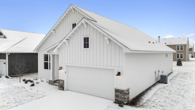 view of snow covered exterior featuring a garage and central AC